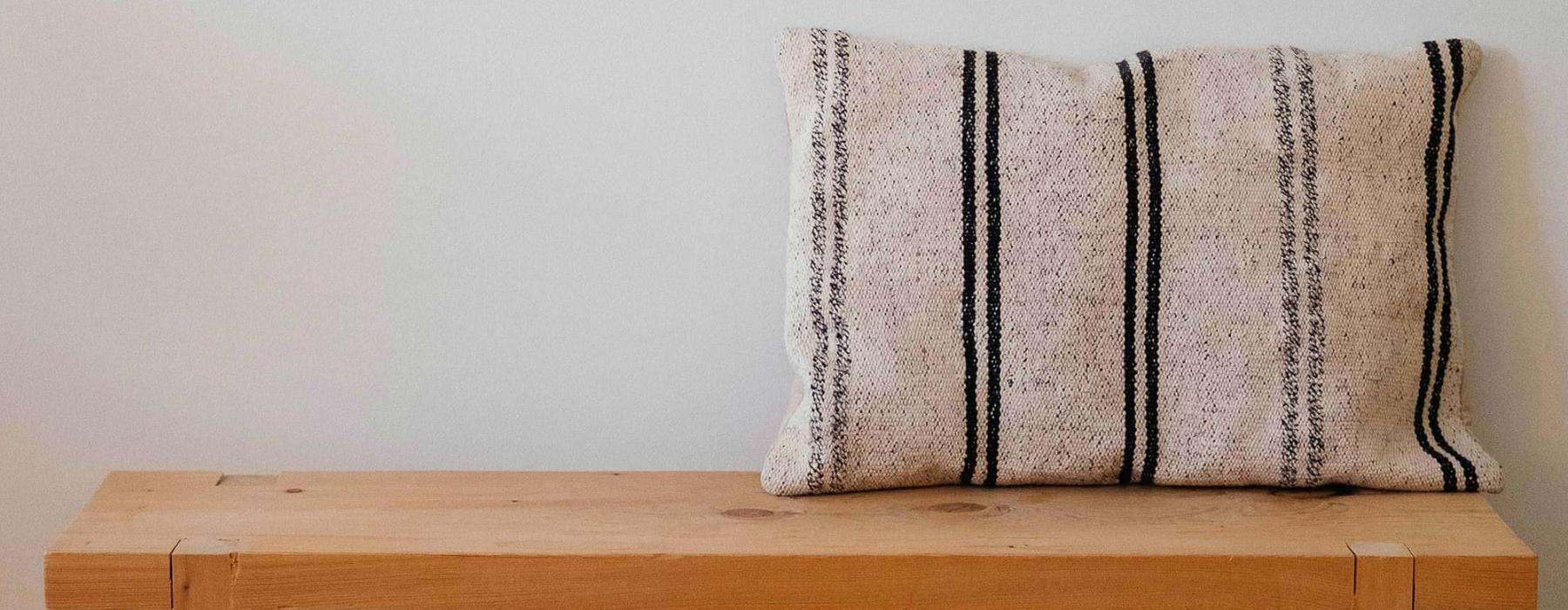 a wooden bench with a striped pillow on it